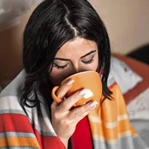 mujer abrigada con una manta bebiendo en taza