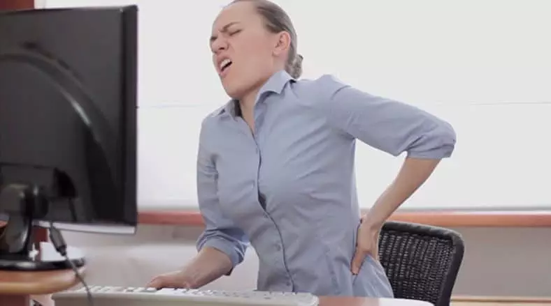 mujer con dolor de espalda de estar sentada en la oficina